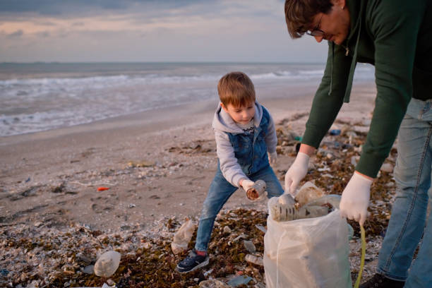 istock Family volunteers cleans a beach by gathering discarded plastic waste. Environmental pollution and ecological problems concept. 1474789965