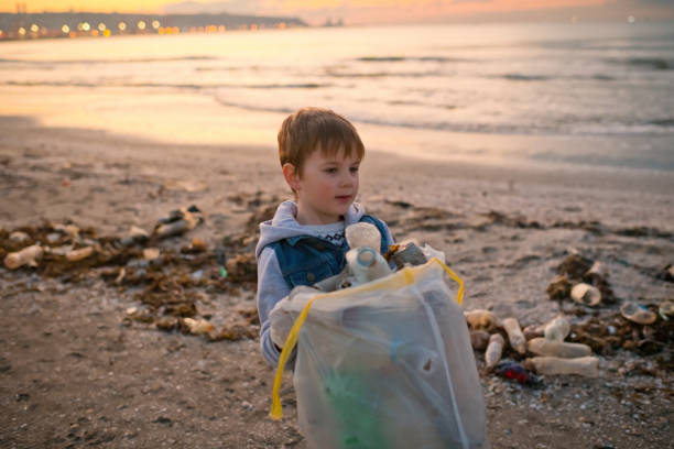 Little boy picking up garbage near the sea