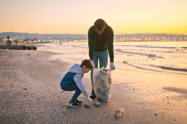 istock Family volunteers cleans a beach by gathering discarded plastic waste. Environmental pollution and ecological problems concept. 1474789999