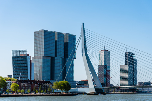 Rotterdam, Netherlands - May 8, 2022: De Rotterdam Skyscraper designed by Rem Koolhaas architect and Erasmusbrug bridge against sky. Contemporary architecture.