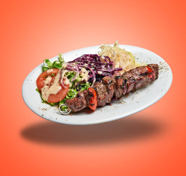 Floating White plate with Lamb skewer and salad on orange gradient background