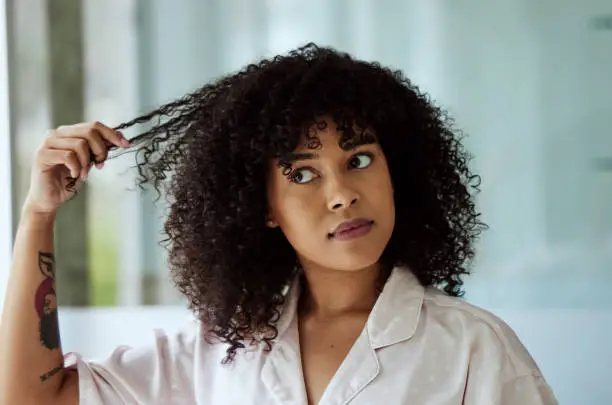 Morning, natural and black woman with hair care bathroom routine feeling curly hair texture. Beauty, self care and african girl thinking of cosmetic treatment in home with thoughtful face.
