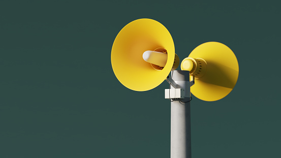 Altavoces amarillos de notificación de megafonía en una publicación sobre fondo verde, representación 3D. Megáfonos de notificación al aire libre para anuncio o alerta de ataque aéreo photo