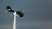 public address notification megaphones on a post, 3d rendering. Outdoor notification loudspeakers for announcement or air raid alert, sky background