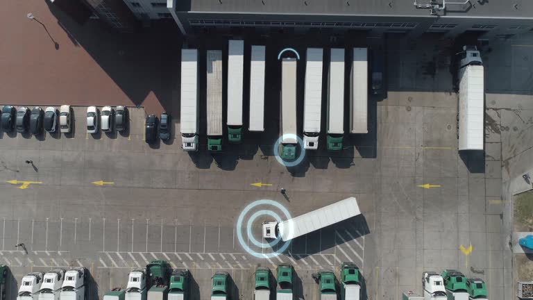 Buildings of logistics center near the highway, the truck leaves parking, artificial intelligence tracks trucks, motion graphics, view from height, a large number of trucks in the parking lot near warehouse, transport tracking system.