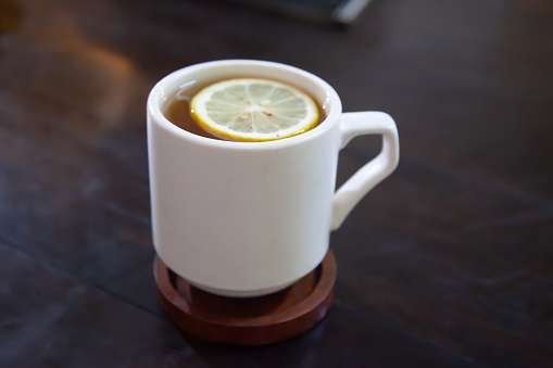 A cup of hot lemon tea on top of a wooden table
