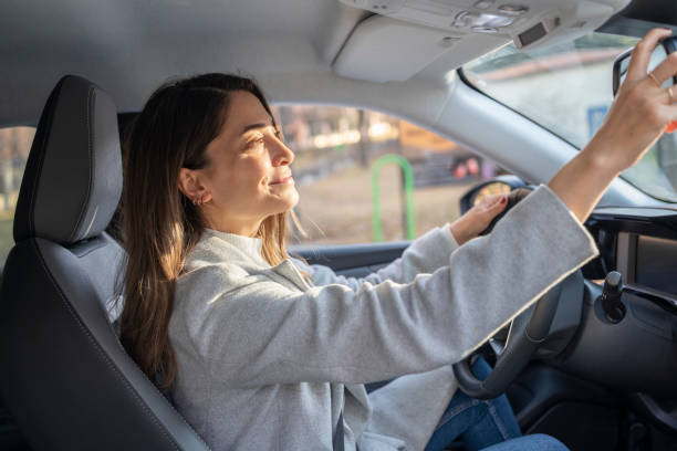 regolazione dello specchietto retrovisore - car insurance women driving foto e immagini stock