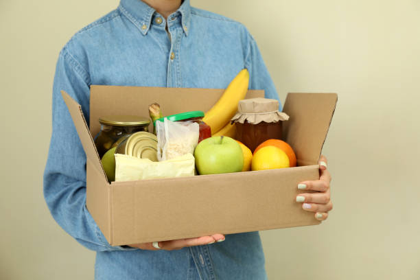 istock Woman holds donation box on beige background 1474797669