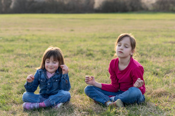 istock Cute happy girls meditating on the meadow during spring day 1474798982