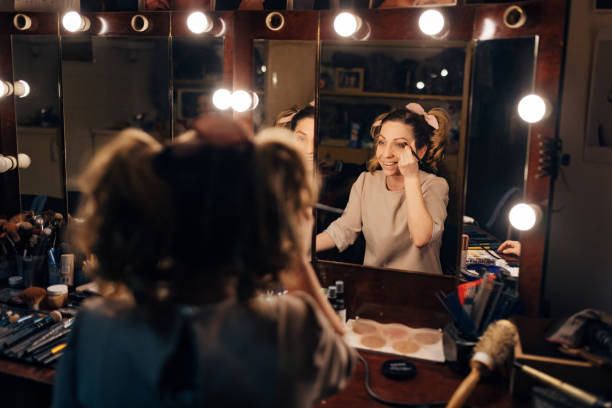 istock Smiling actress applying make-up in dressing room and getting ready for performance 1474800369