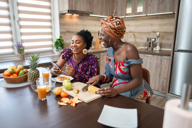 istock Two black female friends looking at the phone while eating fresh fruit in the kitchen 1474801005