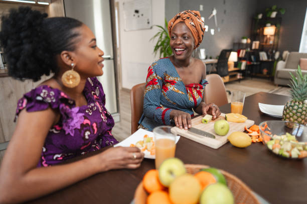 istock Two black female friends having fun while cutting fresh fruit in the kitchen 1474801060