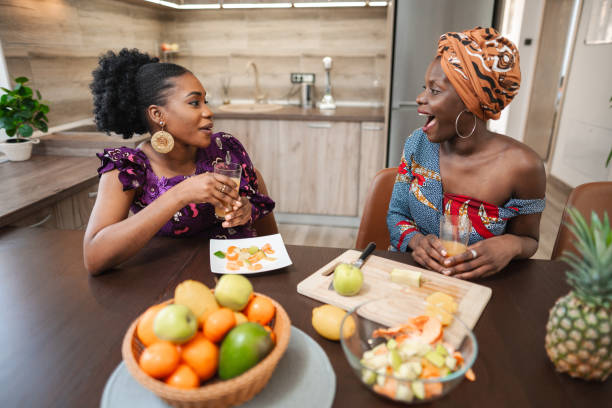 istock Two black female friends having fun while cutting fresh fruit in the kitchen 1474801064