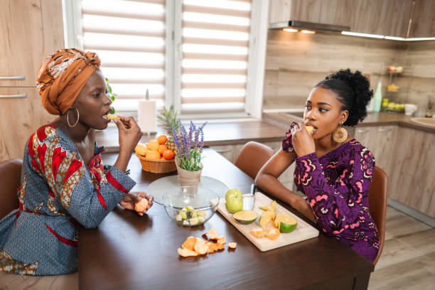 istock Two black female friends having fun while cutting fresh fruit in the kitchen 1474801065