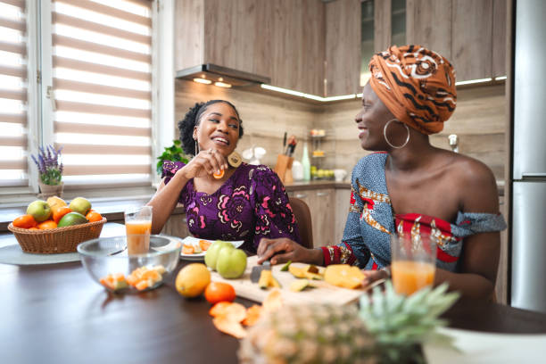 istock Two black female friends having fun while cutting fresh fruit in the kitchen 1474801093