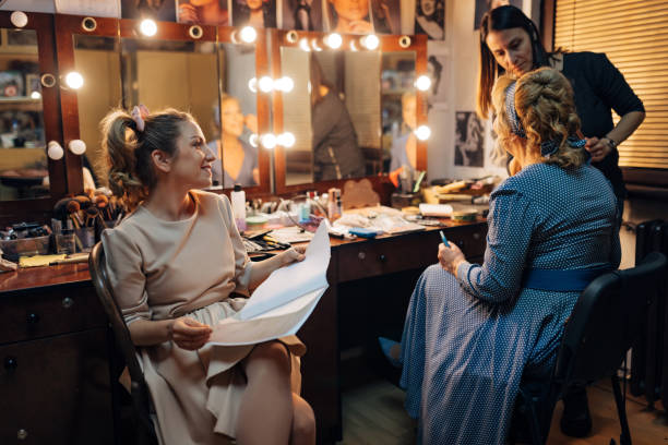 istock A smiling actress holds a script in her hands as she watches a professional make-up artist apply make-up to her senior colleague 1474801102