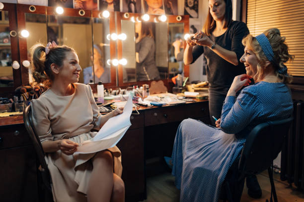 istock A smiling actress holds a script in her hands as she watches a make-up artist apply make-up to her senior colleague 1474801126