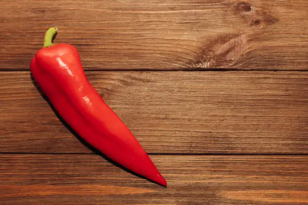 Red capi pepper on a wooden background, space for text.