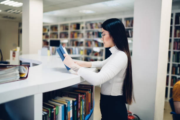 istock Woman reading book at library counter 1474804544