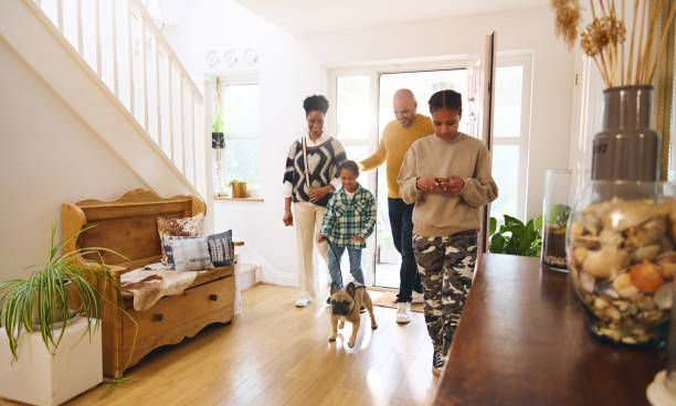 Family arriving home with pet dog, girl using phone
