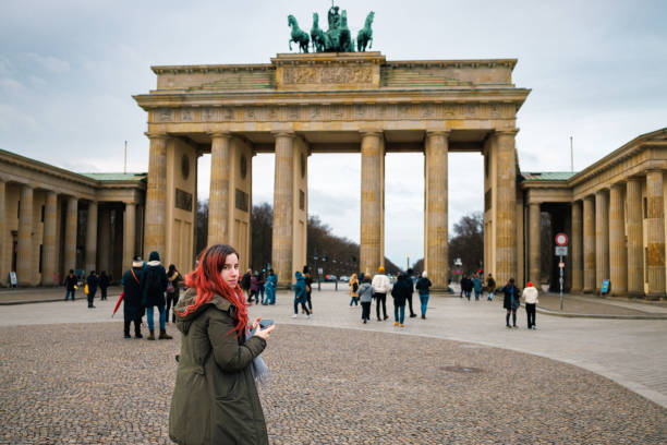istock Young woman standing on town square, looking at camera over shoulder 1474805560