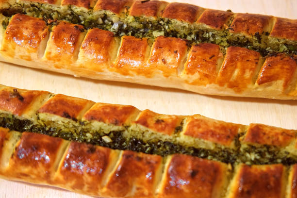 Fresh bread from oven. Handmade French baguette with garlic. Making bread and eco production. Bakery shop and selling rooty. Baking bio bread on rustic wooden table.