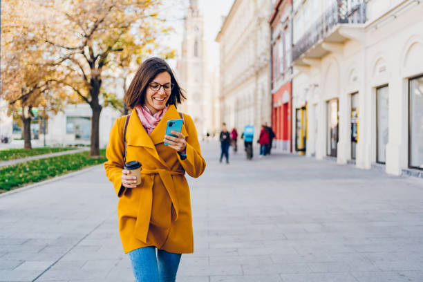 istock A woman walks around the city using a mobile phone 1474808509