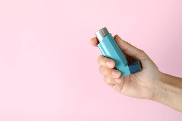 istock Female hand holds asthma inhaler on pink background 1474808611