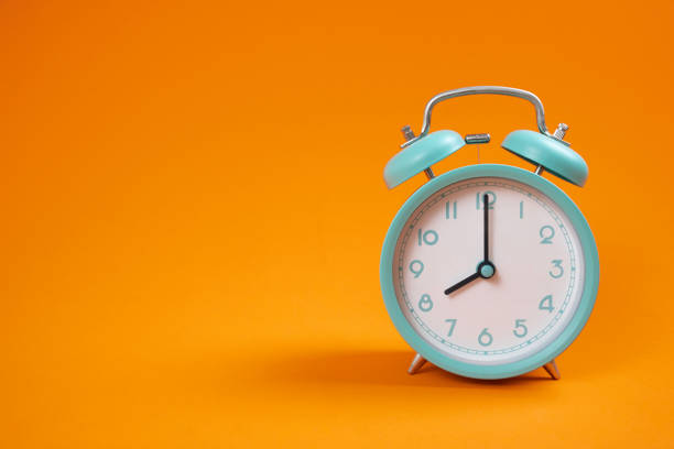 istock Retro green alarm clock on orange table background, vintage style 1474809810