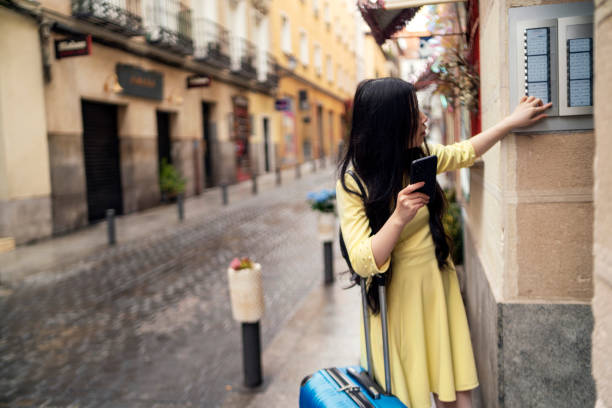 A tourist girl with her suitcase knocking on the door of a tourist flat. stock photo