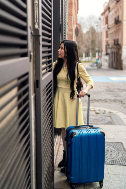 A tourist girl with her suitcase knocking on the door of a tourist flat. stock photo