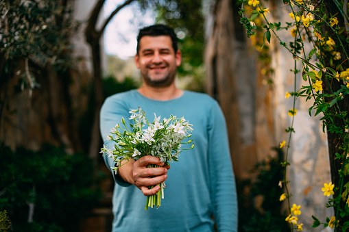 Young Man is Holding a Bouquet of Flowers