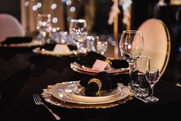 istock Serving, setting table. Wedding set up, dinner table reception. Birthday, baptism, event. Luxury golden decor. Plate decorated linen black napkin and silverware cutlery, glasses. Side view. Closeup. 1474811948