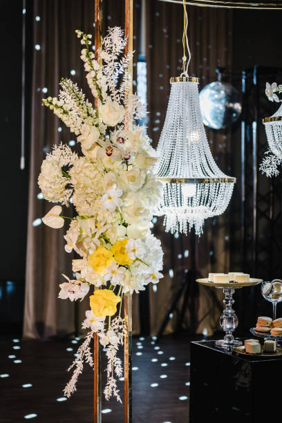 istock Delicious luxury wedding reception. Candy bar. Table with candies, dessert. Arch with large chandelier, flowers in hall restaurant. Golden rich interior with light at night. Birthday, baptism, event. 1474814134