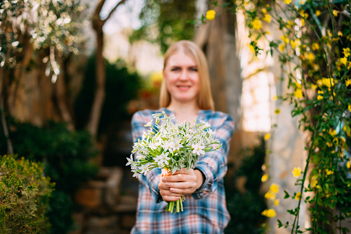 Beautiful Young Woman is Holding a Bouquet of Flowers