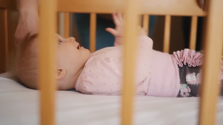 Close-up of a playful newborn in a crib, full of positive emotions