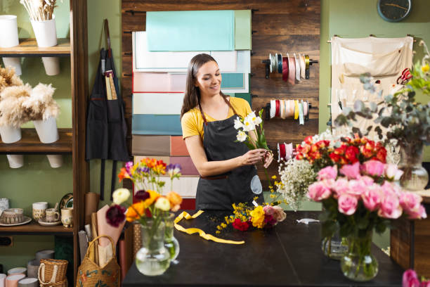istock Cheerful young florist making flowers bouquet 1474821244