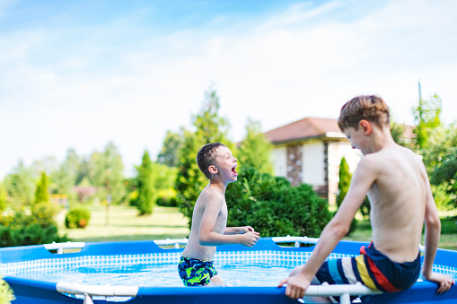 Boys having fun in swimming pool at back yard