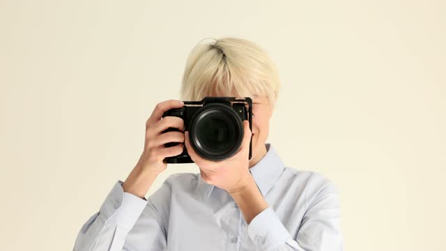 Woman photographer taking pictures on professional camera on white background portrait 4k movie slow motion