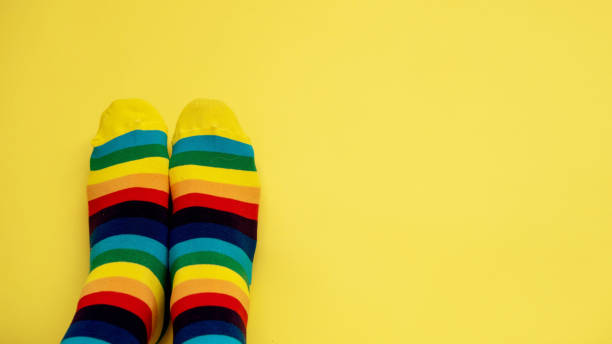 istock legs in rainbow socks and on a monochrome yellow background, a layout with a place for text and a place to copy. pair of rainbow-colored socks. Symbol LGBT 1474825595