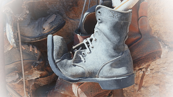 An old worn-out boot hangs as a decorative element. Sunny weather. Outdoor. White Vignette