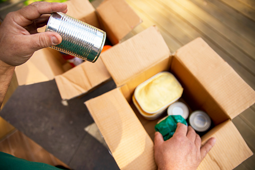 Senior Man in need unpacking food from a donation box