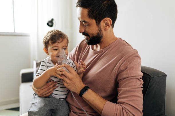 portret chłopca wdychającego leki w nebulizatorze z ojcem w domu. - nebulizer zdjęcia i obrazy z banku zdjęć