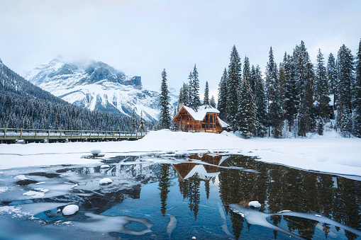 A winter scenic of a rustic, timber-framed lodge in the Canadian backcountry. Horizontal colour image. British Columbia, Canada. Rocky Mountains. Image taken at night with log cabin structure lit with moonlight and starlight. 