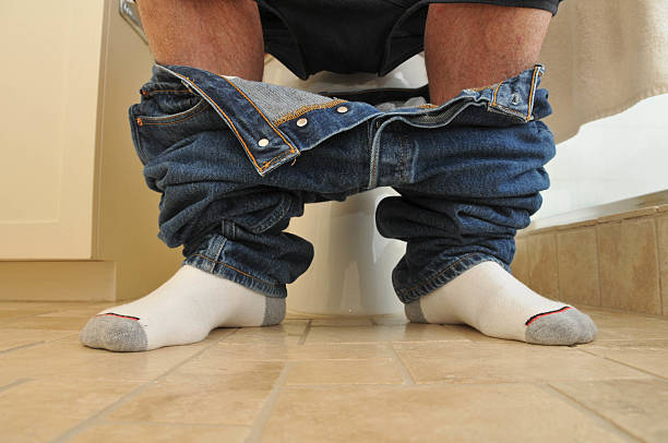 Man with pants down sitting on the toilet stock photo