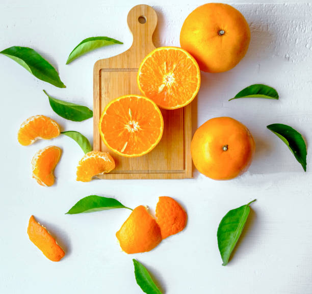 agrumi freschi con arance tagliate, frutta e foglie d'arancio su fondo di legno bianco - isolated on white orange juice ripe leaf foto e immagini stock