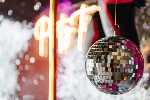 Disco ball. Happy New Year 2024. Bright glowing disco ball on photo booth with decor text party time. Light blur background for wedding or birthday. Zone, wall decorated black and silver balloons.