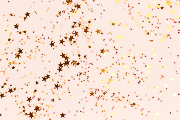 istock Shiny gold colored stars and crystals confetti on a beige background. 1474834979