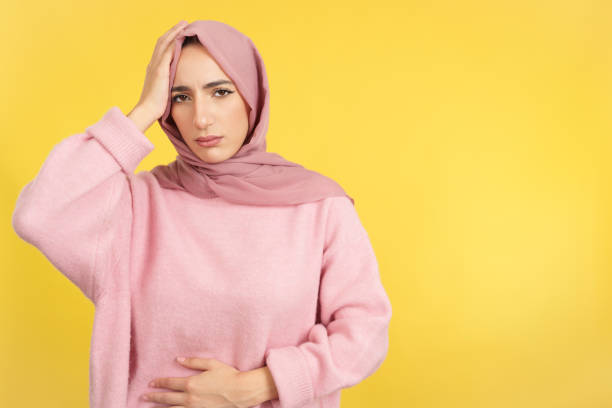 muslim woman gesturing bodily discomfort and headache - women guilt uncomfortable human face imagens e fotografias de stock