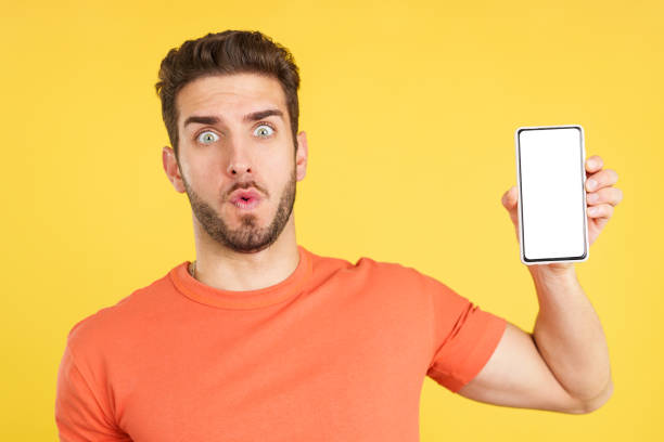istock Surprised caucasian man holding a mobile with a blank screen 1474838530